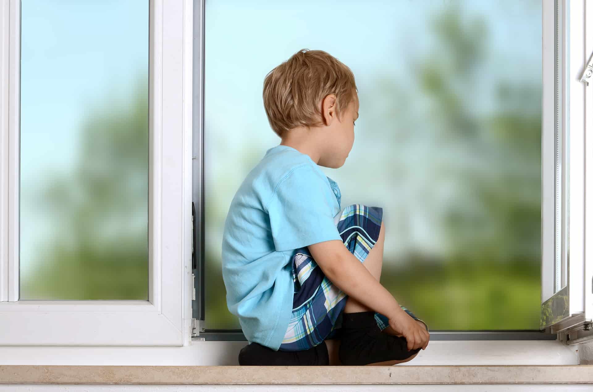 Chłopczyk siedzący na parpecie otwartego okna